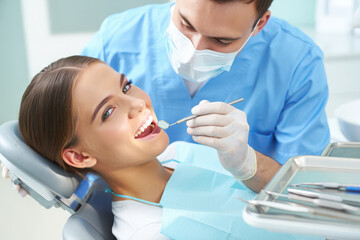 A dentist examining a smiling young womans teeth in a modern dental clinic, highlighting oral healthcare