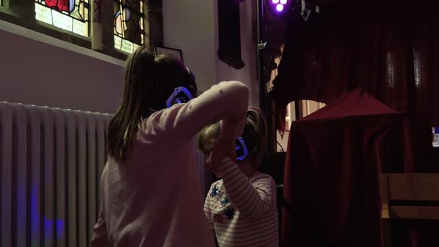 4K: Grils dancing at Silent Disco wearing headphones. Sisters having at indoor party. Stock Video Clip Footage