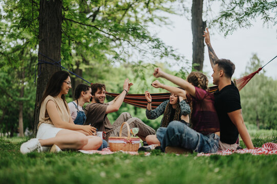 A group of young adults sitting together on picnic blankets, socializing and relaxing in nature during a pleasant day. Trees and greenery create a peaceful environment perfect for leisure and bonding.