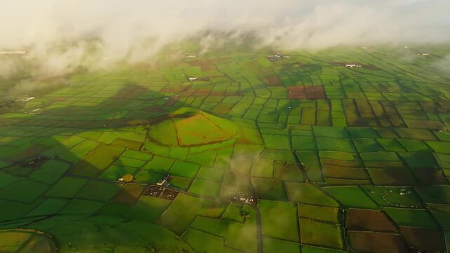 Aerial view of the lush green Pico Dona Joana mountain, its slopes a vibrant contrast to the patchwork fields of geod&eacute;sico, Acores, Portugal.