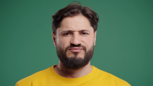 Tired Annoyed Man Sighs, Rolls Eyes On Green Background. Displeased Expression