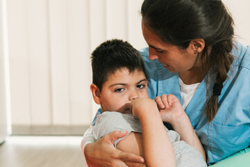 Physiotherapist embracing child with cerebral palsy during therapy session