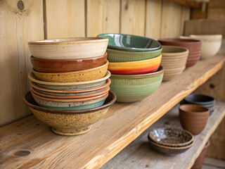 Handmade pottery bowls stacked on a rustic wooden shelf