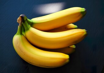 A bunch of ripe yellow bananas on a dark textured surface