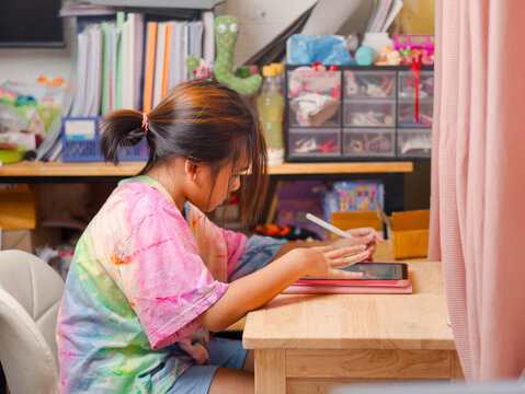 Two elementary school girls are studying at their desks at home. Two cute schoolgirls are diligently doing their homework.