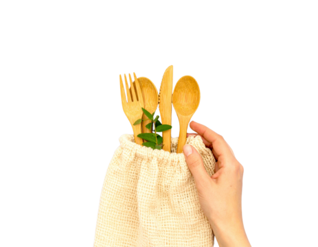 Hand holding bamboo reusable cutlery set in fabric pouch, isolated on a transparent background
