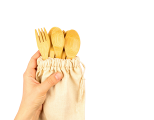Hand holding bamboo reusable cutlery set in fabric pouch, isolated on a transparent background
