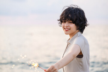 夕暮れの海辺で花火を楽しむ女性モデルの柔らかなボケ感を活かしたポートレート
