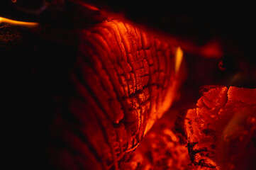 Cozy background of burning logs in a fireplace. Close-up of glowing embers and warm flames. Concept...