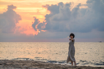 夕暮れの海辺で花火を楽しむ女性モデルの柔らかなボケ感を活かしたポートレート