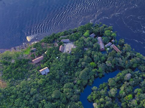 Aerial view of stilt houses nestle amidst the emerald canopy, where the river's embrace meets the land's edge, creating a vibrant tapestry of nature, Guainia, Guain&Atilde;&shy;a, Colombia.