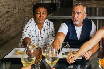 Friends toasting white wine glasses at restaurant table
