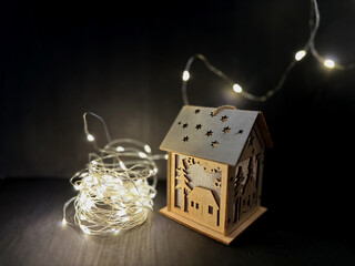 Wooden Christmas village lantern and tangled string lights glowing warmly in the dark. Peaceful...