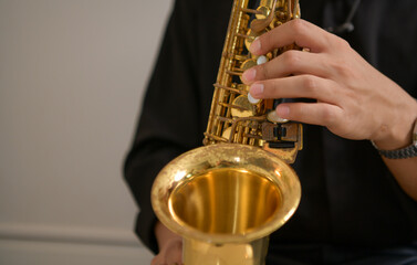 Naklejka premium Young Asian man playing saxophone indoors in a cozy room with soft lighting
