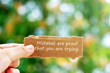 Hand holding piece of paper with inspirational quotes mistake are proof that you are trying