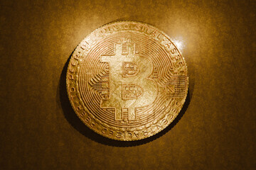 Golden Bitcoin coin on textured background, representing cryptocurrency, blockchain, digital currency, and financial innovation. Shiny metallic design. Business and investment, creative idea