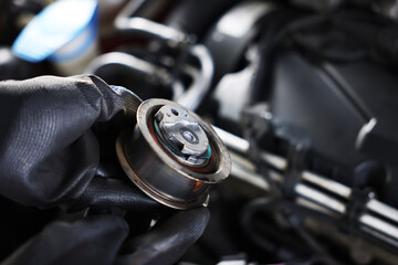 Auto part. Professional mechanic with idler-wheel near open hood of car indoors, closeup. Space for...
