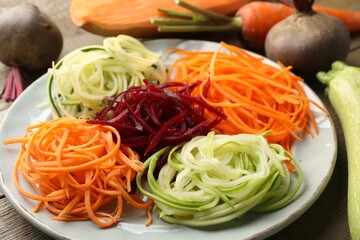 Different noodles and vegetables on wooden table, closeup
