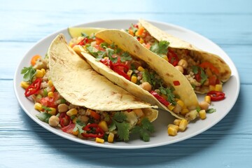Tasty vegetarian tacos with chickpeas, corn and quinoa served on light blue wooden table, closeup