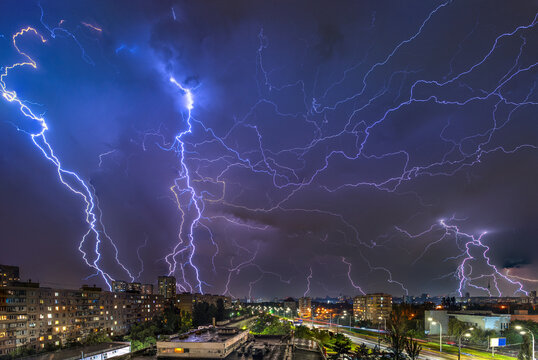 Powerful lightning storm over Kyiv at night, illuminating residential buildings and city streets. A dramatic display of nature's force captured during a summer thunderstorm.