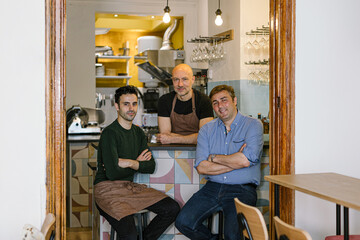 Three cheerful restaurant owners posing in their newly opened bistro