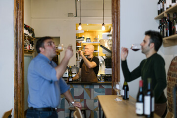 Wine tasting experience: sommelier and customers enjoying wine in enoteca