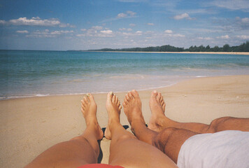 Couple relaxing on tropical beach showing feet, film photography