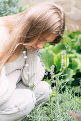 Young girl enjoys nature by smelling lavender flowers in a garden on a sunny day