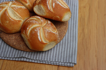 Decorated bread rolls on gray striped napkin on wooden table