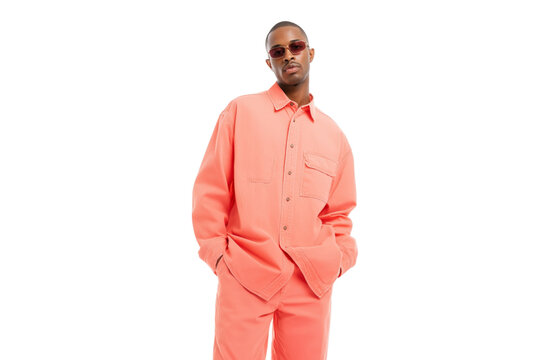 man standing confidently in fashionable coral-colored outfit with sunglasses isolated on white background