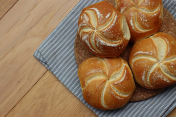 Top view of decorated bread rolls on gray striped napkin on wooden table