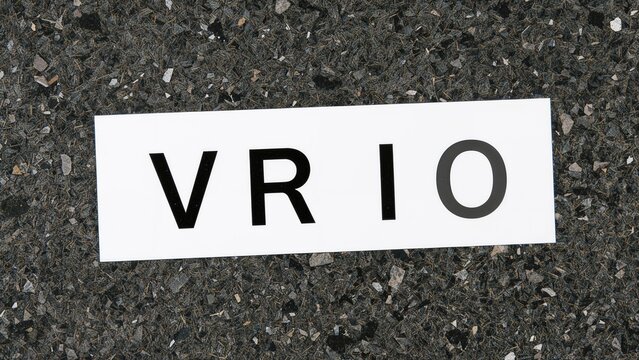 Business model illustration with a VRIO abbreviation card emphasizing Value, Rarity, Inimitability, and Organization in a professional office setting