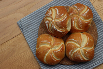 Top view of decorated bread rolls on gray striped napkin on wooden table