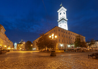 Night view of Lviv City Hall and Rynok Square with illuminated tower and historic buildings in Lviv...