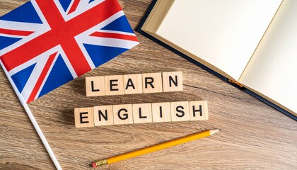 "LEARN ENGLISH" written on separate wooden cube blocks, placed beside a small British flag with an open book and a pencil on a desk background