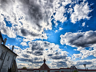 Clouds drift across a vibrant blue sky over a historic structure in a picturesque landscape during a sunny day