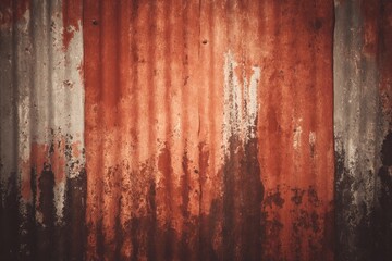 Rusty corrugated metal wall with weathered textures and faded colors in an outdoor setting during daylight