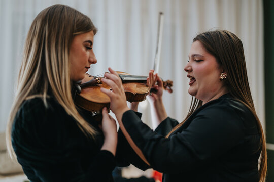 Music tutor passionately assists her student in a violin lesson, showing technique and posture. The intimate moment highlights dedication, learning, creativity, and connection in a warm indoor setting