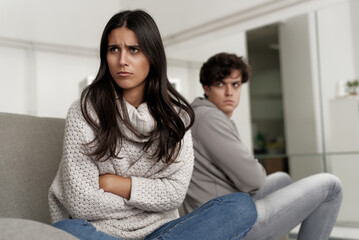 Couple sitting apart in a modern living room during an emotional conversation filled with tension...