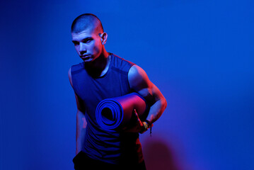 Young man preparing for yoga session in dramatic lighting at a modern studio during evening hours