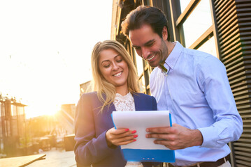 Couple discussing plans outdoors during golden hour near a city waterfront