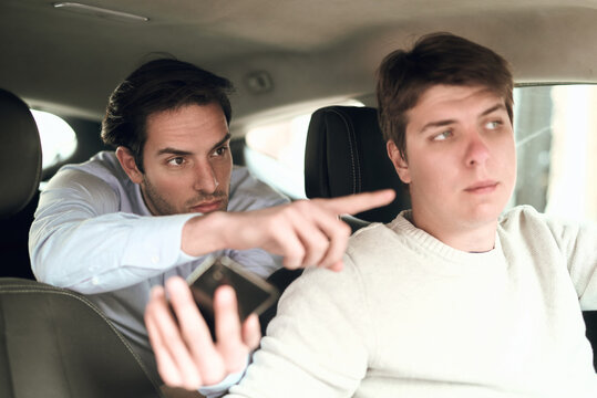 Tense conversation between two men inside a car on a busy street during the day