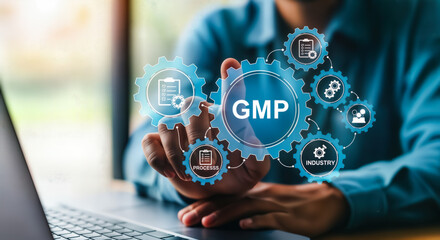 A persons finger touches a digital interface displaying the gmp acronym surrounded by interconnected gears, symbolizing good manufacturing practices and quality control in various industries