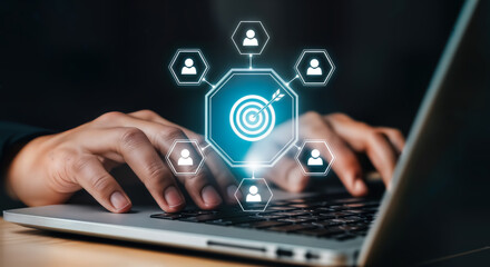 Person typing on a laptop with a digital network of goals and people icons connecting to a central target, symbolizing business strategy and teamwork for success