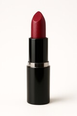 Obraz premium Vibrant red lipstick in elegant black and silver tube on clean white.