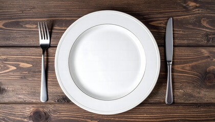 Top view of a clean empty white plate with fork and knife on a rustic wooden table. Concept for dining and healthy eating.
