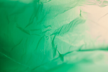 Extreme close up of green empty plastic bag background. The plastic surface is wrinkly and tattered...