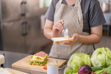 Woman spreading mayonnaise on bread for a sandwich.
