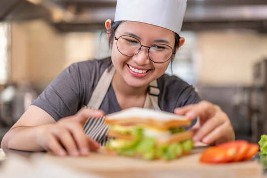 Asian Female Chef Assembling Fresh Sandwich in Kitchen