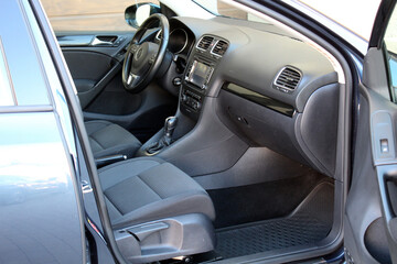 Passenger side view of a modern car interior with black fabric seats, central console with...